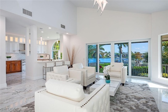 living room with a water view, sink, and a high ceiling