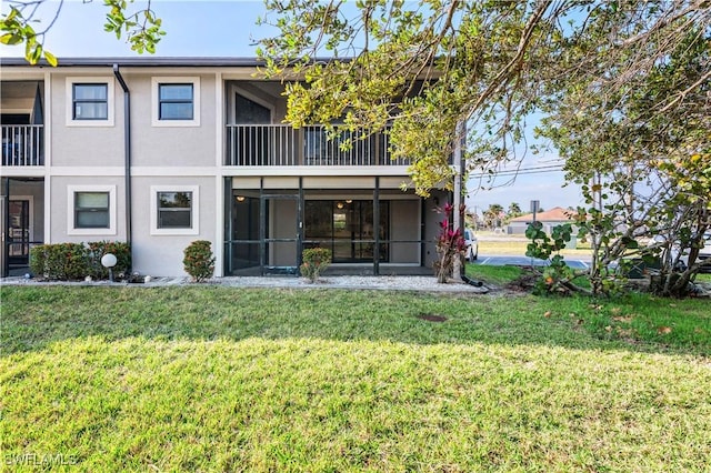 rear view of property with a yard and a sunroom