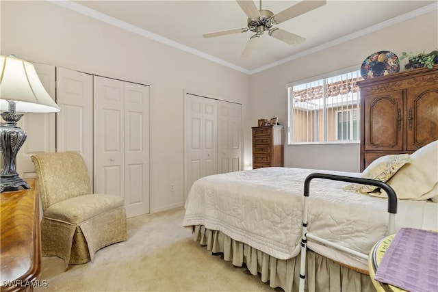 carpeted bedroom featuring ceiling fan, ornamental molding, and two closets