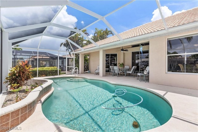 view of swimming pool with glass enclosure, ceiling fan, and a patio area