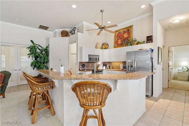 kitchen with a kitchen bar, white cabinetry, light stone countertops, and appliances with stainless steel finishes