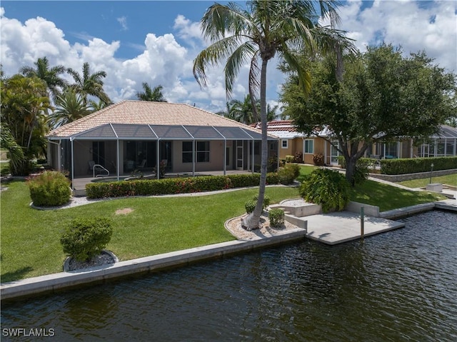 back of house with a lawn, glass enclosure, and a water view