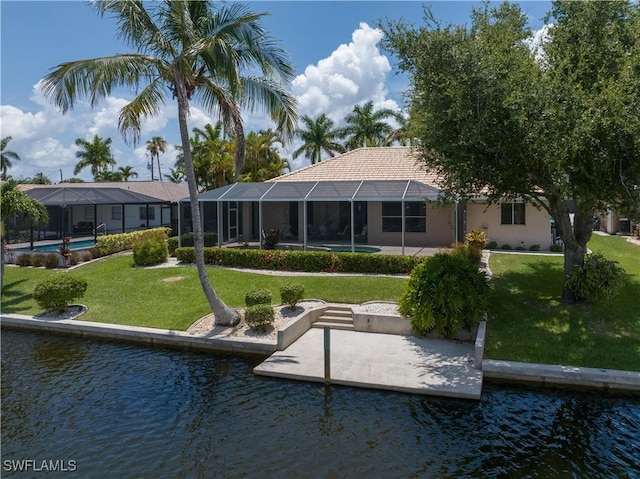 rear view of property with a lanai, a yard, and a water view