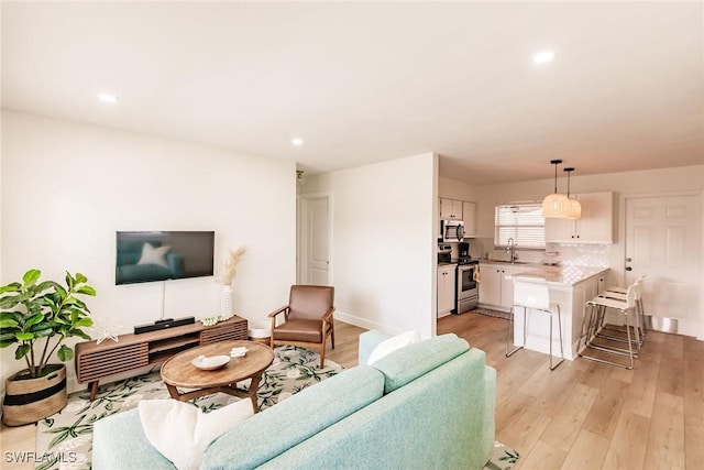 living room with light hardwood / wood-style floors and sink