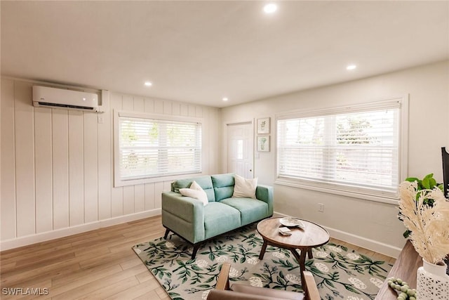 living room featuring light hardwood / wood-style floors, a wall unit AC, and a healthy amount of sunlight