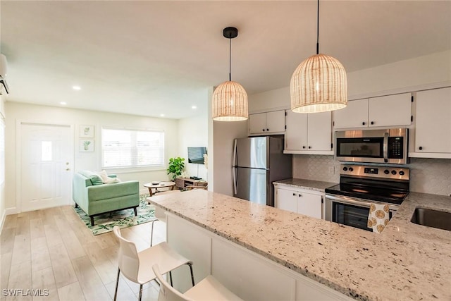 kitchen with backsplash, light stone countertops, appliances with stainless steel finishes, decorative light fixtures, and kitchen peninsula