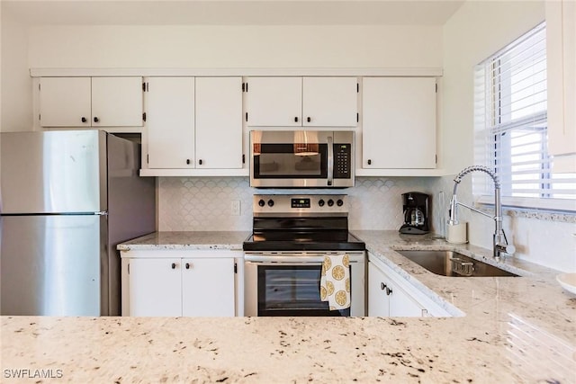 kitchen featuring tasteful backsplash, sink, white cabinets, and stainless steel appliances