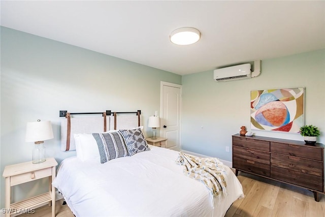 bedroom featuring a wall mounted air conditioner and light hardwood / wood-style flooring