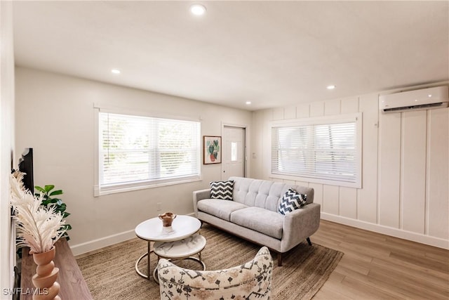 living room featuring a healthy amount of sunlight, light hardwood / wood-style floors, and a wall mounted air conditioner