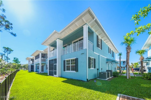 rear view of property with central air condition unit and a lawn