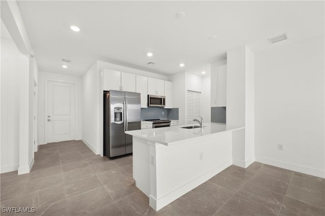 kitchen with white cabinetry, sink, kitchen peninsula, decorative backsplash, and appliances with stainless steel finishes