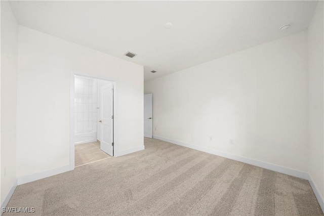 unfurnished bedroom featuring ensuite bath and light carpet