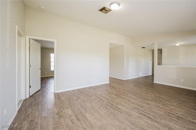 unfurnished room featuring wood finished floors, visible vents, and baseboards