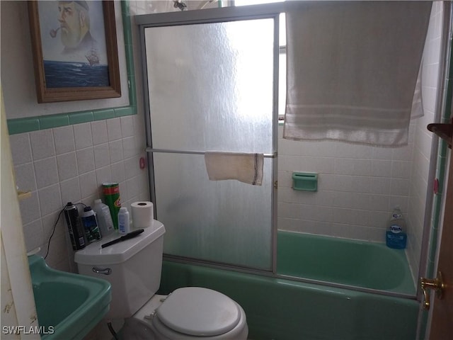 full bathroom featuring sink, toilet, tile walls, and combined bath / shower with glass door