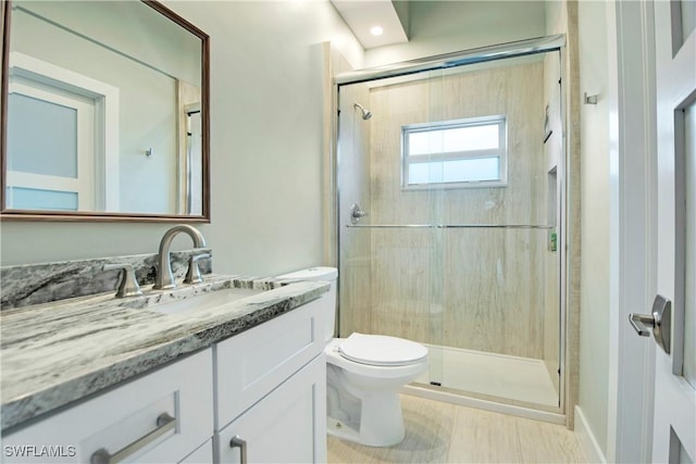 bathroom with a shower with door, vanity, and toilet