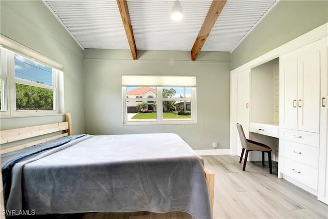 bedroom featuring beamed ceiling and light wood-type flooring