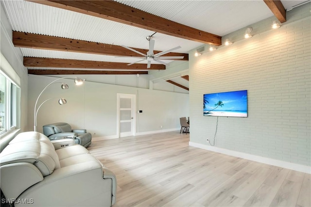 living room featuring beamed ceiling, ceiling fan, brick wall, and light hardwood / wood-style flooring