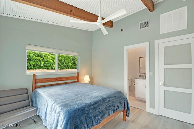 bedroom featuring beam ceiling, ceiling fan, light hardwood / wood-style flooring, and ensuite bathroom