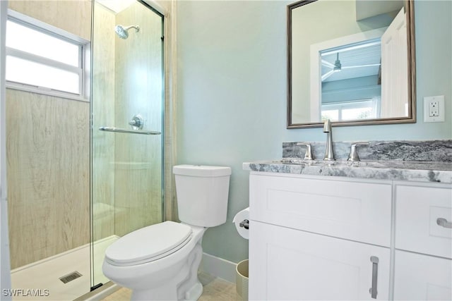 bathroom featuring vanity, toilet, a shower with shower door, and a wealth of natural light