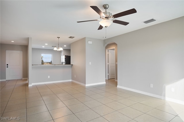 tiled empty room featuring ceiling fan with notable chandelier