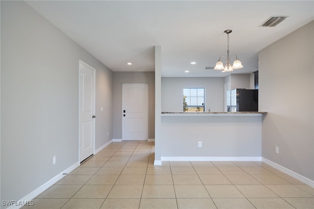 kitchen featuring decorative light fixtures, stainless steel fridge, light tile patterned floors, light stone counters, and kitchen peninsula