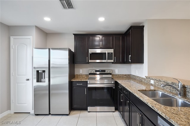 kitchen featuring light stone countertops, appliances with stainless steel finishes, sink, and light tile patterned floors