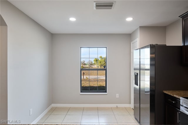 kitchen with dark stone countertops, light tile patterned floors, and stainless steel fridge with ice dispenser