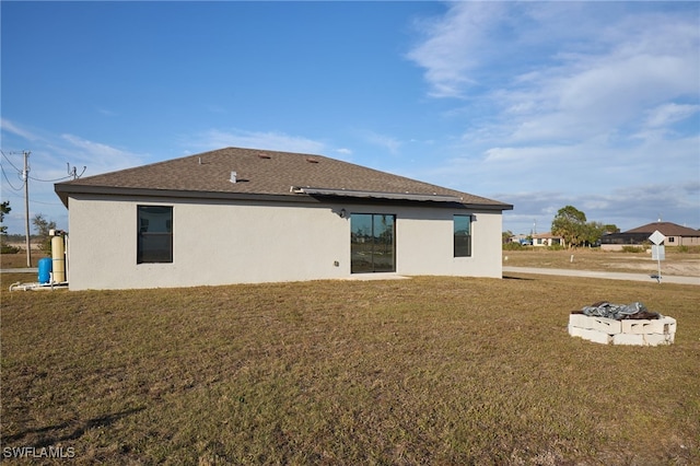 back of property featuring a fire pit and a lawn