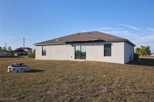 back of house featuring a fire pit, a lawn, and central air condition unit