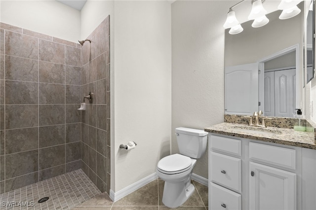 bathroom featuring tiled shower, vanity, toilet, and tile patterned flooring