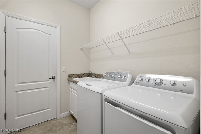 washroom featuring cabinets, light tile patterned floors, washing machine and dryer, and sink