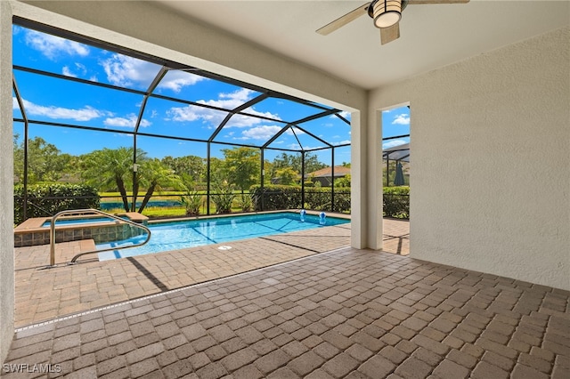 view of pool featuring glass enclosure, ceiling fan, a patio, and an in ground hot tub