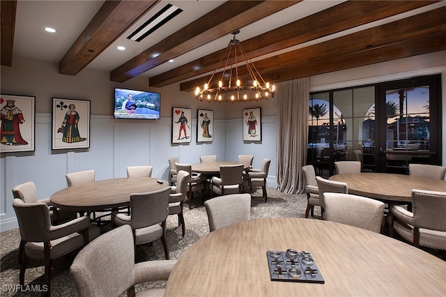 dining space with carpet flooring, beam ceiling, and a notable chandelier