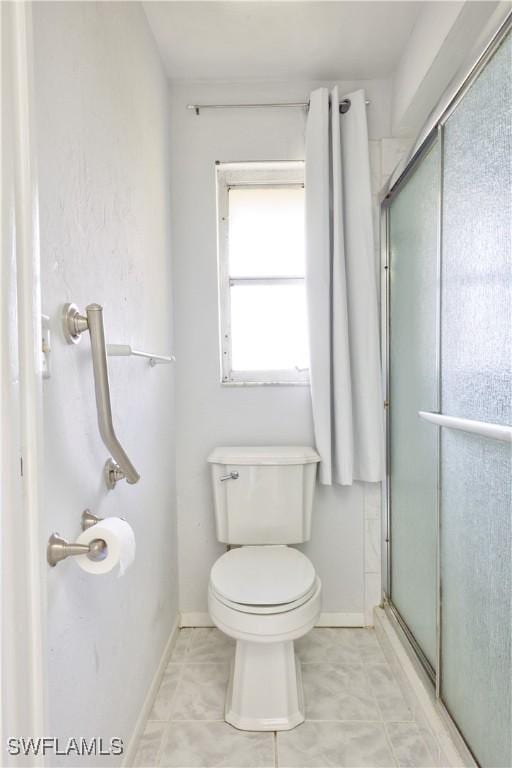 bathroom featuring toilet, a shower with door, and tile patterned flooring