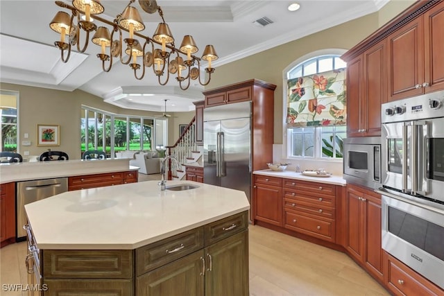 kitchen featuring sink, built in appliances, a chandelier, decorative light fixtures, and a kitchen island with sink