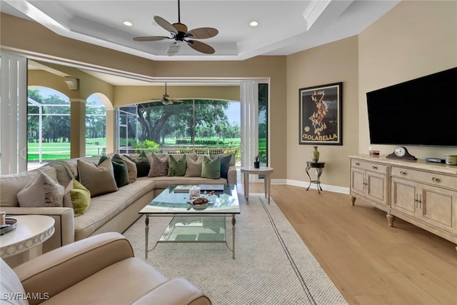 living room featuring ceiling fan, light hardwood / wood-style floors, and a raised ceiling