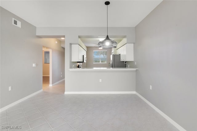 kitchen featuring pendant lighting, white cabinets, kitchen peninsula, stainless steel refrigerator, and light tile patterned floors