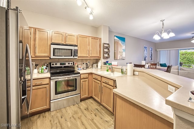 kitchen featuring tasteful backsplash, a notable chandelier, pendant lighting, sink, and stainless steel appliances