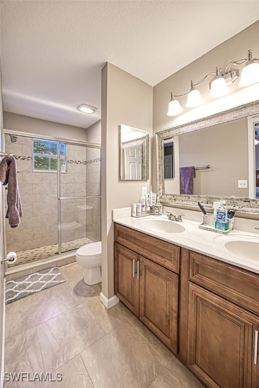 bathroom featuring a textured ceiling, toilet, walk in shower, and vanity