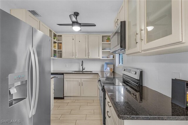 kitchen featuring appliances with stainless steel finishes, ceiling fan, dark stone countertops, and sink