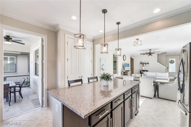 kitchen with ceiling fan, dark brown cabinetry, stainless steel refrigerator, hanging light fixtures, and light stone countertops