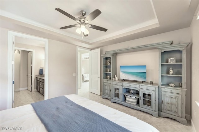 bedroom featuring connected bathroom, ceiling fan, and a tray ceiling