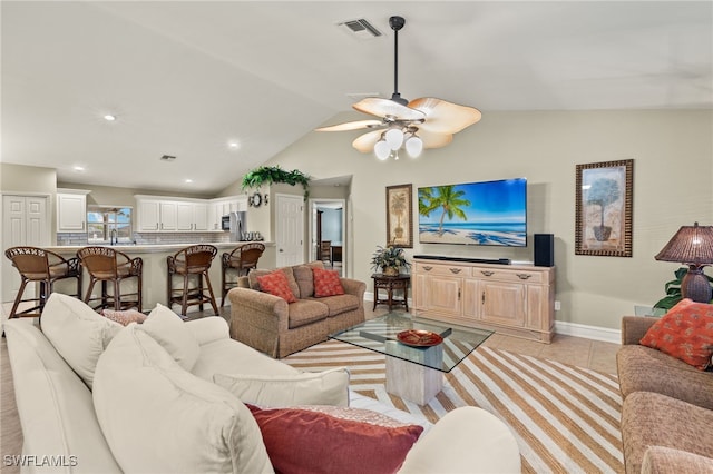 living room featuring ceiling fan, light tile patterned floors, and vaulted ceiling