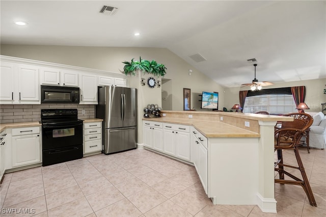 kitchen featuring white cabinetry, kitchen peninsula, a breakfast bar area, decorative backsplash, and black appliances