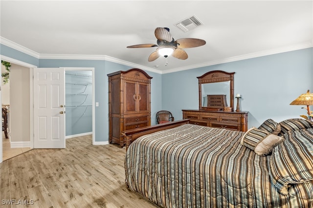 bedroom featuring light hardwood / wood-style floors, a spacious closet, ceiling fan, and crown molding