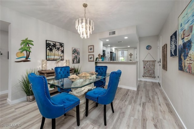 dining room with baseboards, visible vents, wood finished floors, and a chandelier