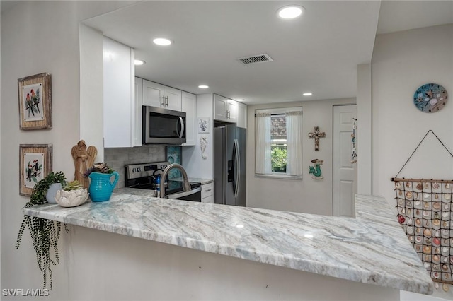kitchen with light stone countertops, stainless steel appliances, a peninsula, decorative backsplash, and visible vents