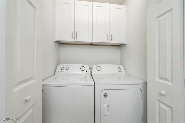 clothes washing area with cabinets and washing machine and clothes dryer