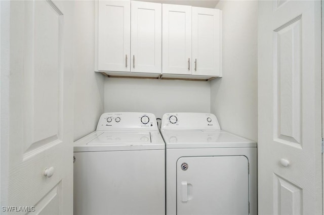 washroom featuring washing machine and clothes dryer and cabinet space