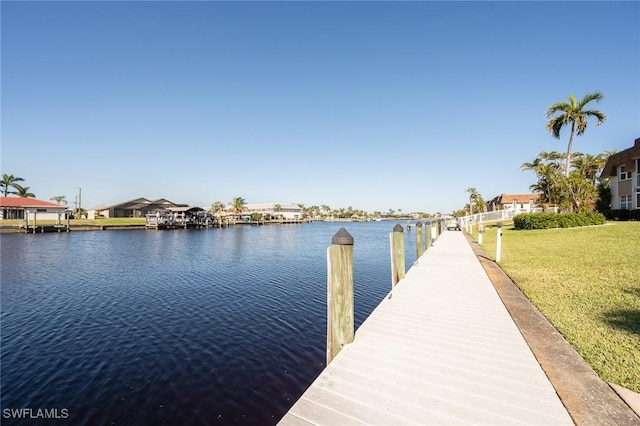view of dock featuring a lawn, a water view, and a residential view